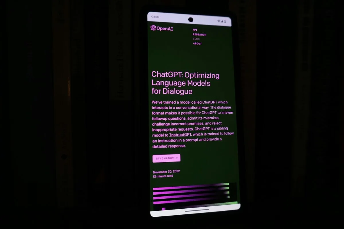 Smartphone im Dunkeln zeigt die OpenAI-Website mit ChatGPT