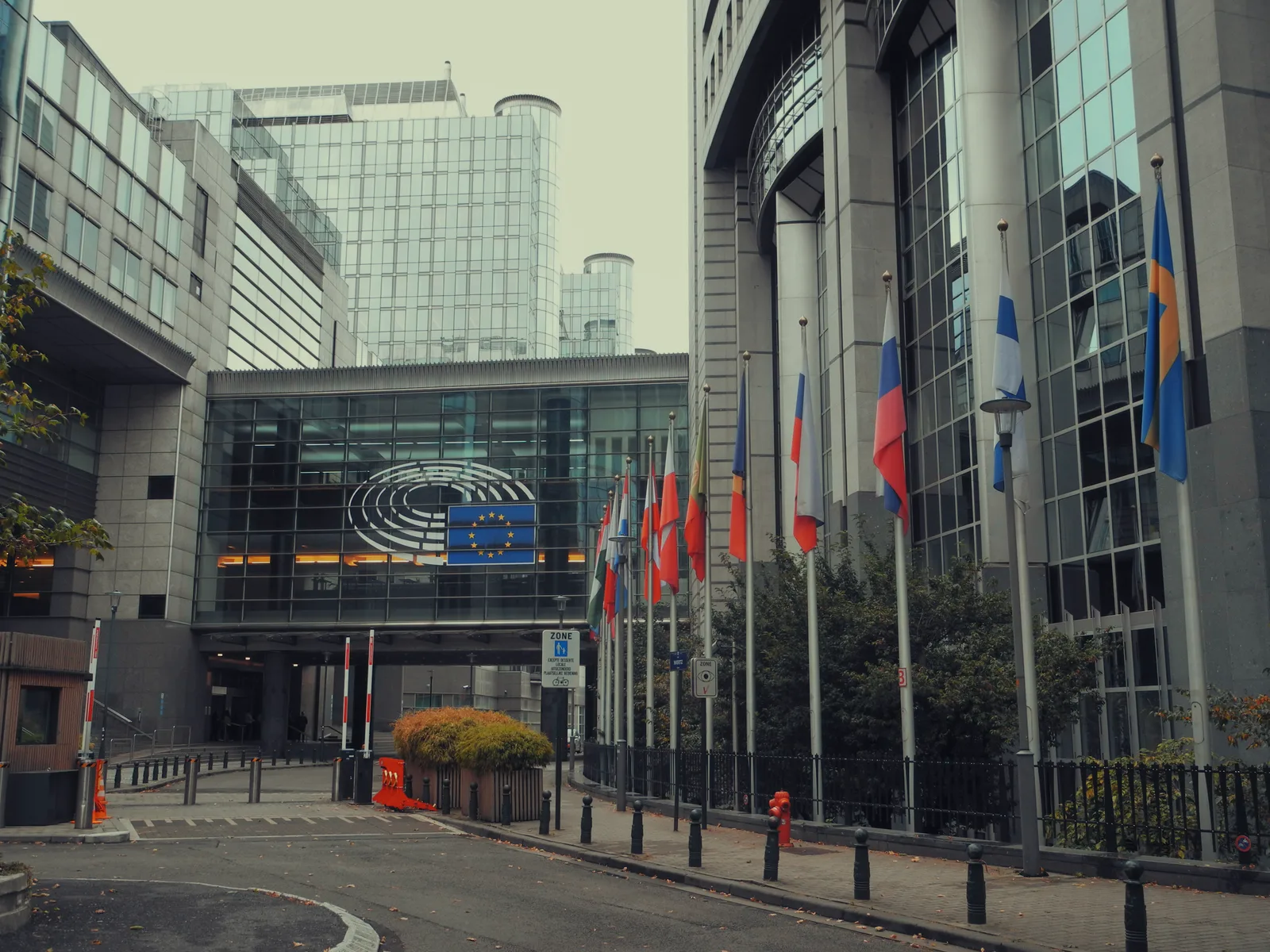 Gebäude des Europäischen Parlaments in Brüssel mit wehenden Flaggen der Europäischen Union davor