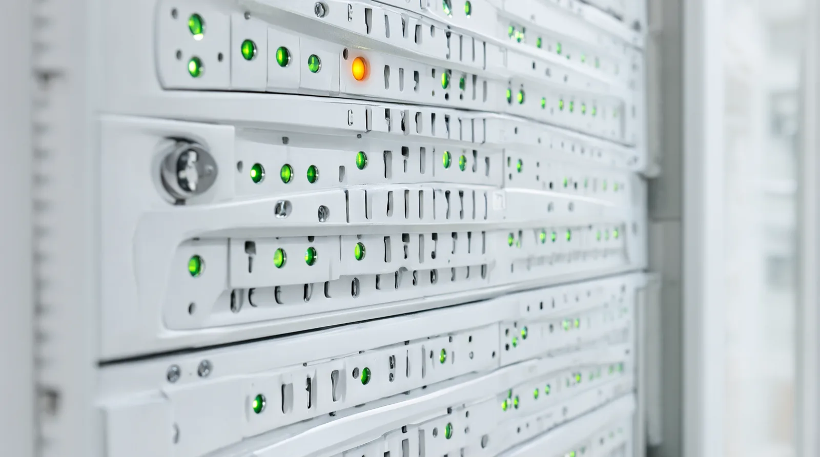 Weißes Server-Rack in einem hellen Rechenzentrum, zwischen vielen grünen Statuslampen leuchtet eine einzelne orange Warnlampe