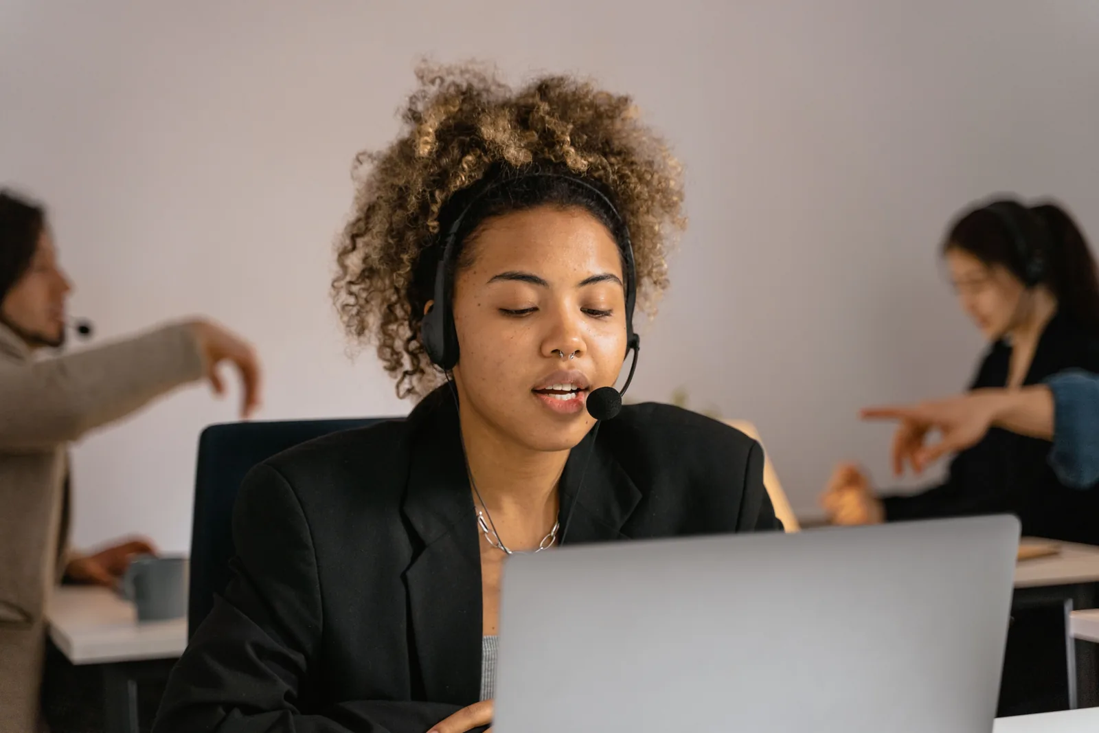Supportmitarbeiterin mit Headset arbeitet an einem Laptop in einem Büro