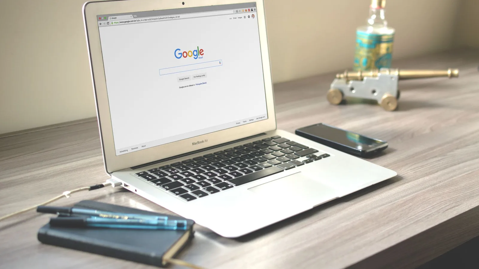 Laptop mit geöffneter Google-Startseite auf einem Schreibtisch, daneben ein Smartphone