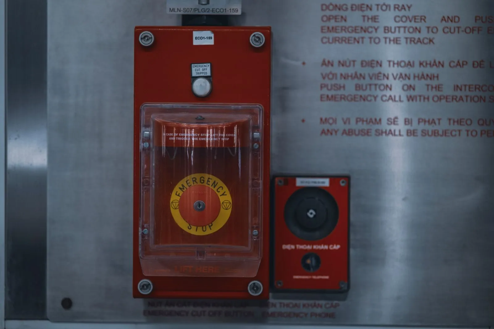Roter Notaus-Schalter unter einer Schutzabdeckung an einer Metallwand