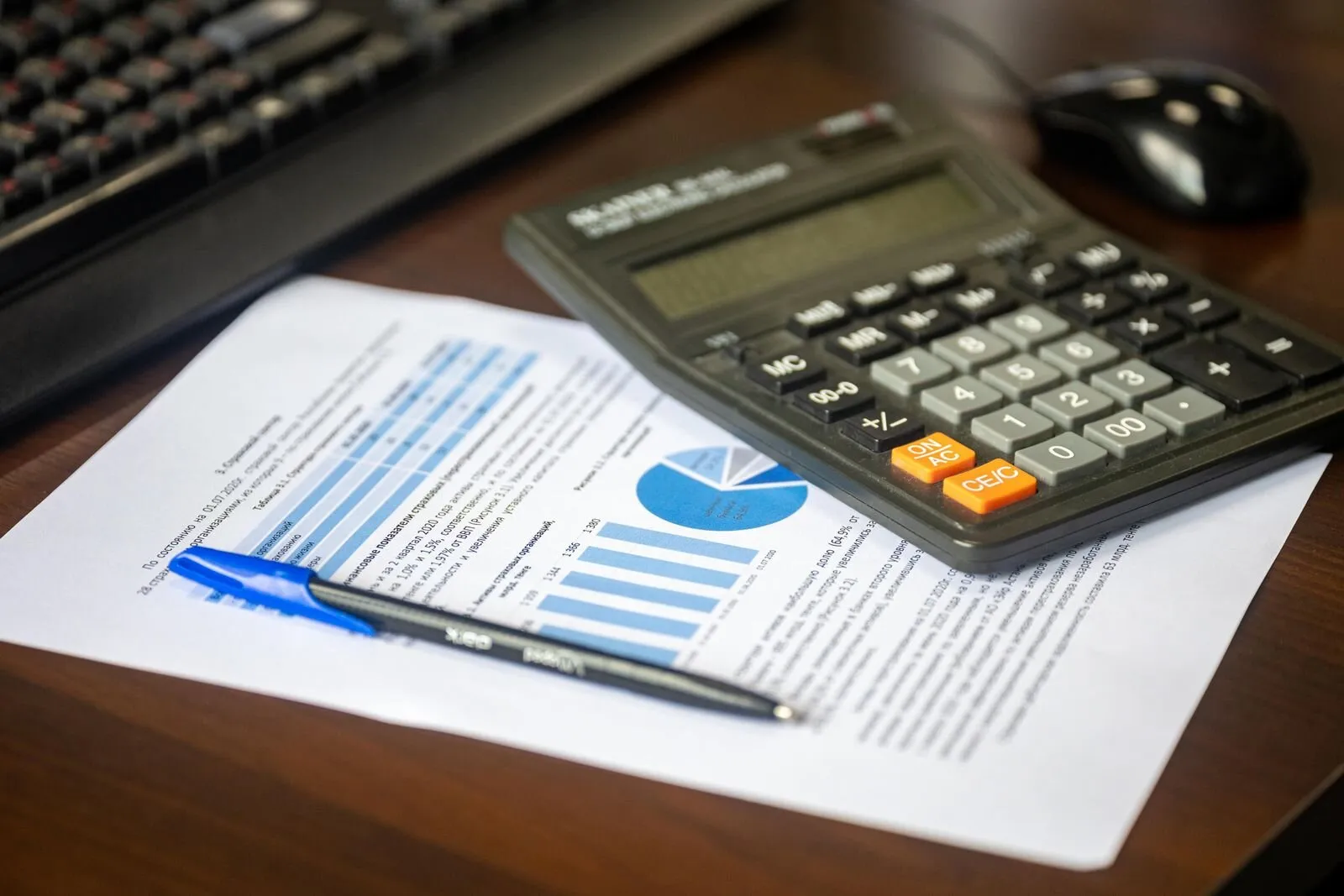 Schreibtisch mit Taschenrechner, Finanzbericht und Stift
