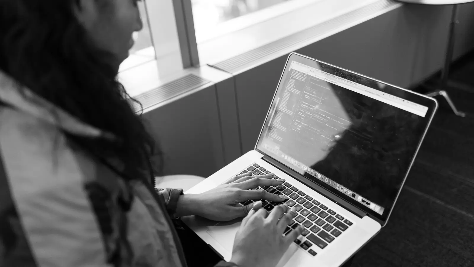 Person tippt Programmcode auf einem Laptop - Symbolbild für einen Coding-Agenten