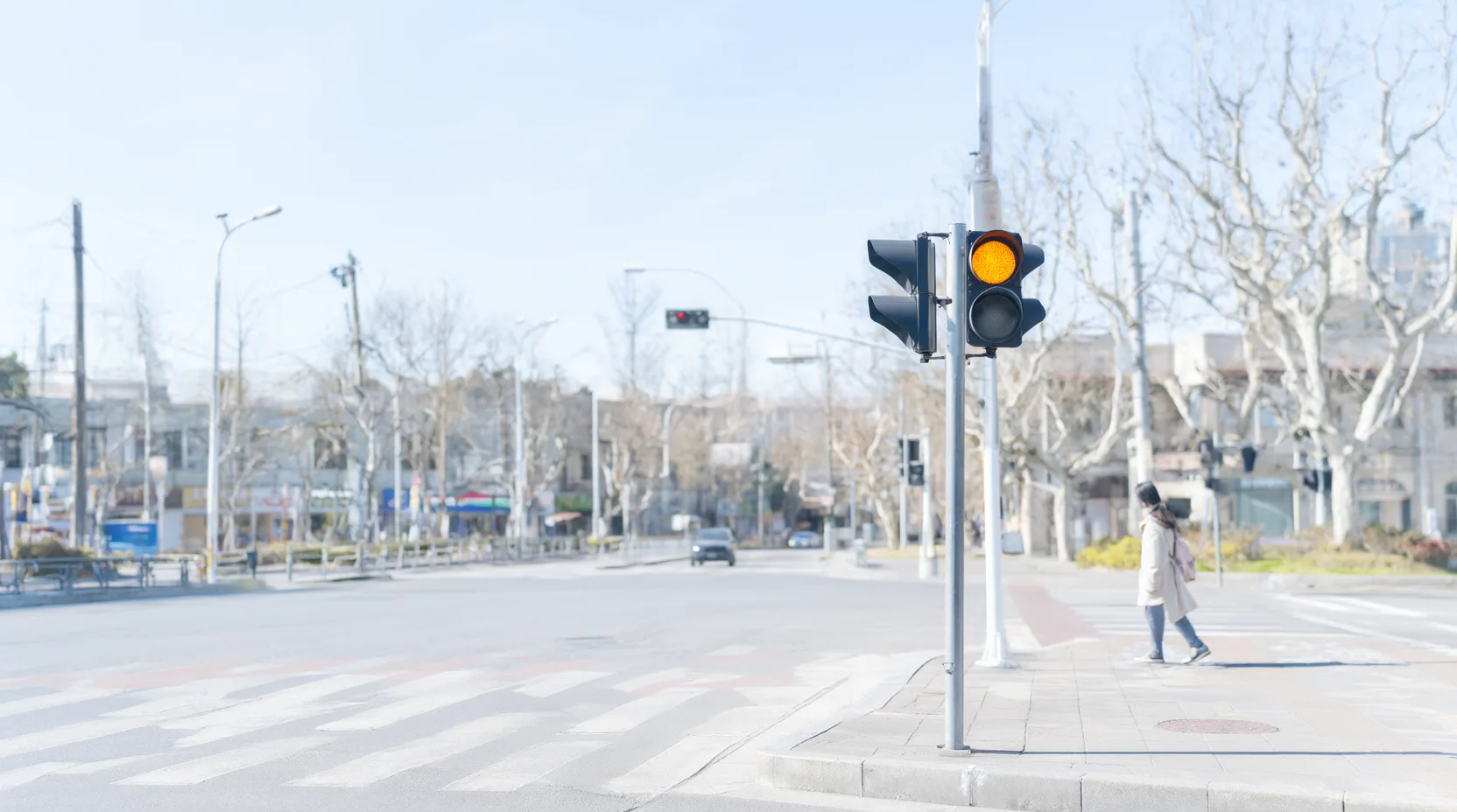 Eine Verkehrsampel zeigt Gelb an einer hellen, sonnigen Straßenkreuzung