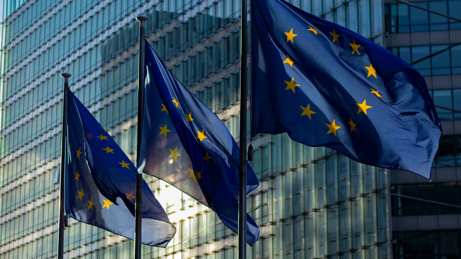 Wehende Flaggen der Europäischen Union vor der Glasfassade der EU-Kommission in Brüssel