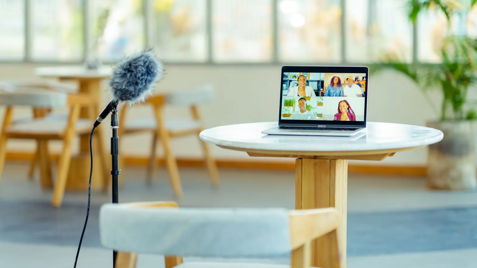 Schreibtisch mit aufgeklapptem Laptop und einem Mikrofon auf einem Stativ