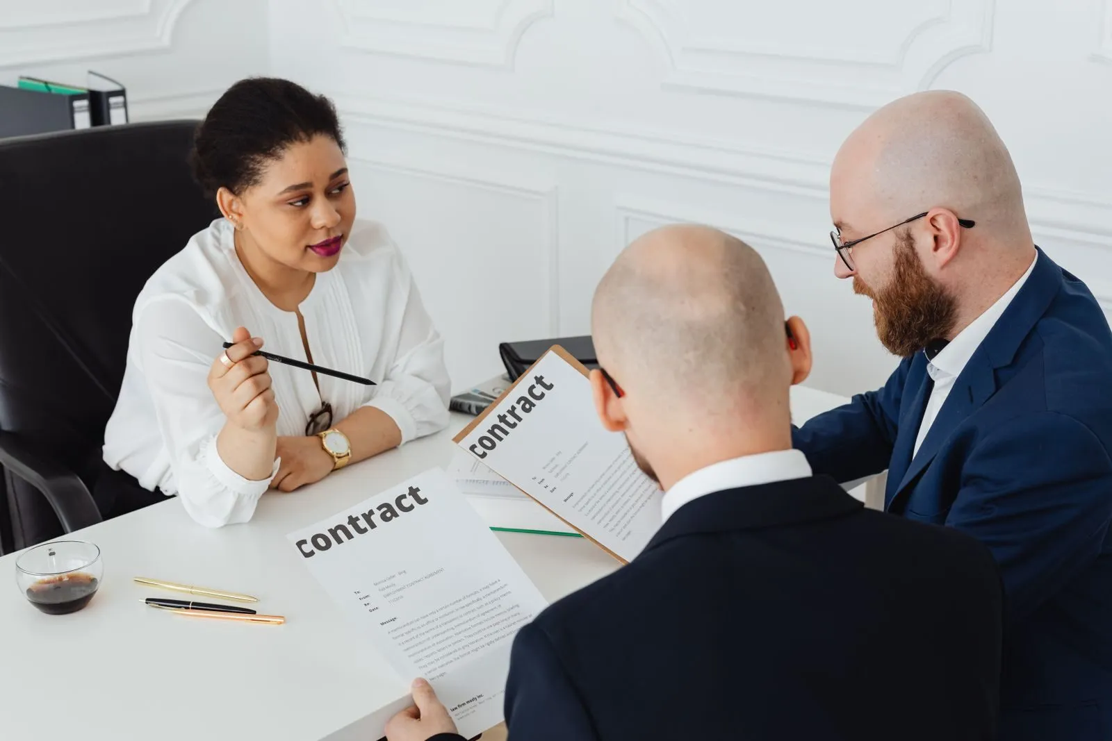 Drei Geschäftsleute besprechen einen Vertrag in einem hellen Büro