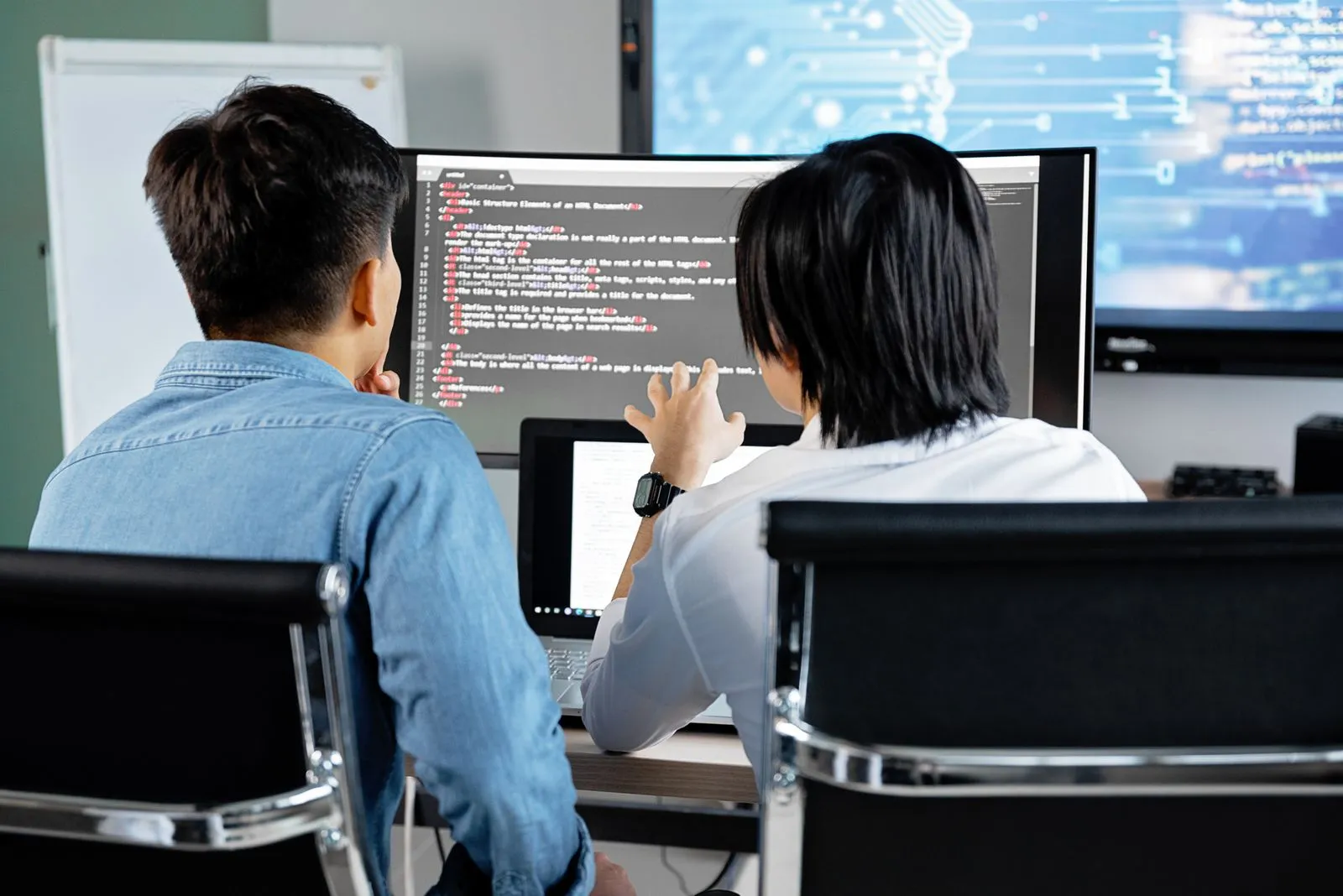 Zwei Entwickler besprechen Code an einem Bildschirm im Büro
