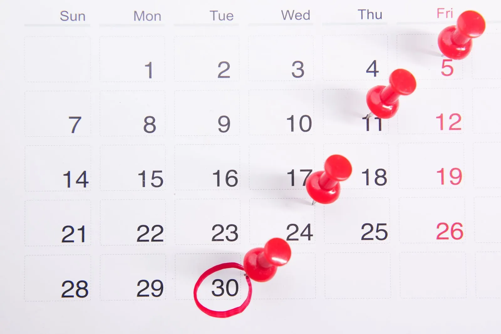 Kalender mit roten Stecknadeln, ein Datum ist rot eingekreist