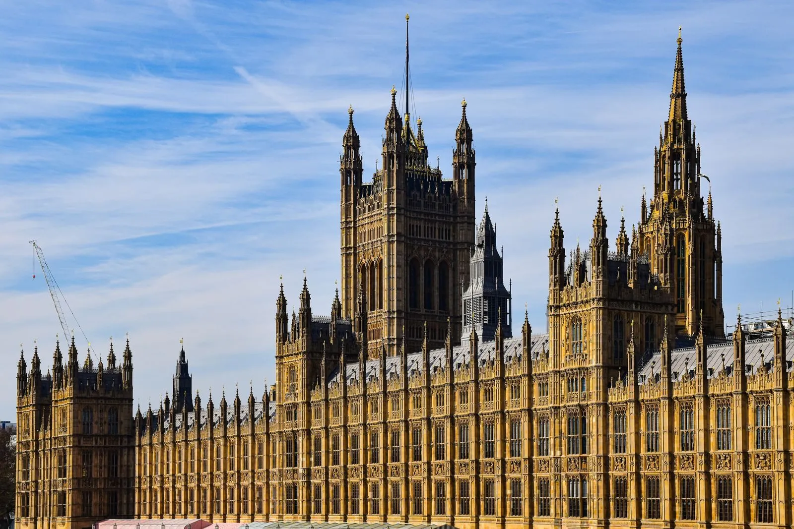 Der Palast von Westminster mit dem Uhrturm an der Themse in London unter blauem Himmel