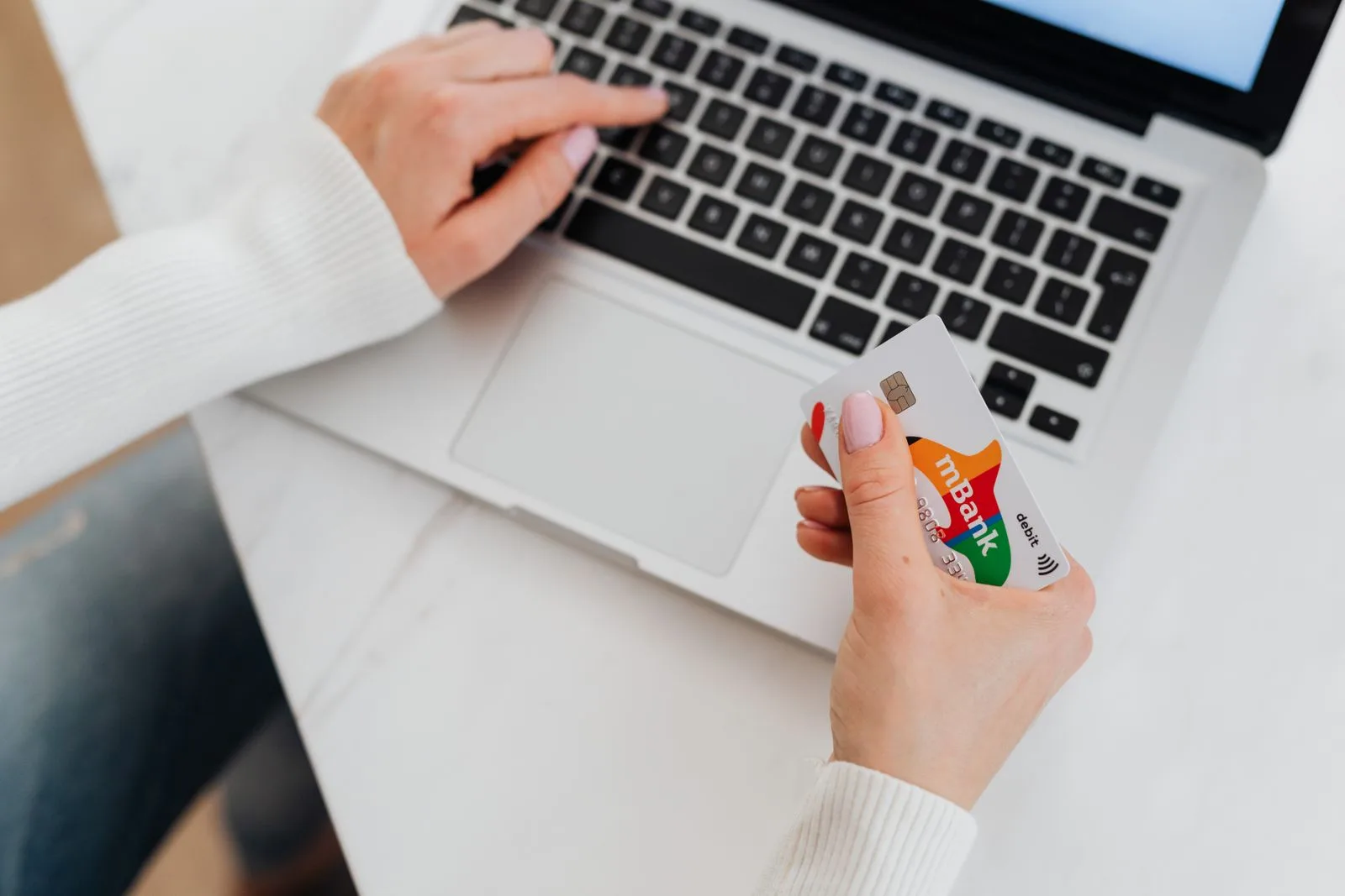 Nahaufnahme einer Person am Laptop, die eine Kreditkarte für eine Online-Zahlung in der Hand hält