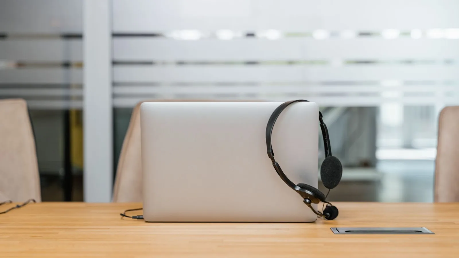 Laptop mit Headset auf einem Holztisch, vorbereitet für ein Online-Meeting