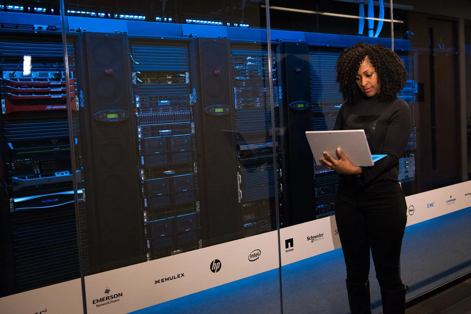 Technikerin mit Laptop überwacht Server in einem Rechenzentrum
