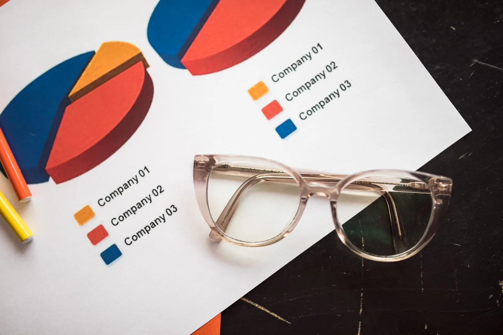 Ausgedruckte Geschäftsdiagramme mit Balken- und Kurvenverläufen auf einem Schreibtisch neben einer Brille
