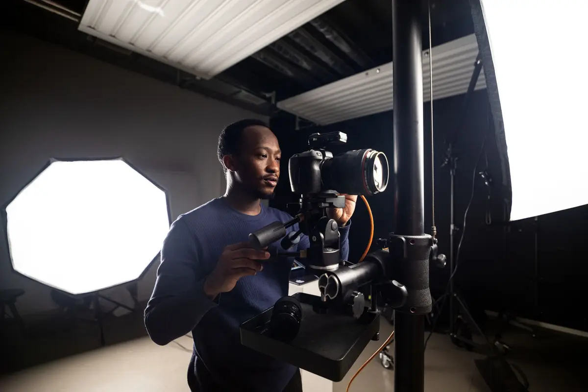 Fotograf richtet im Studio eine Kamera zwischen Lichtstativen aus