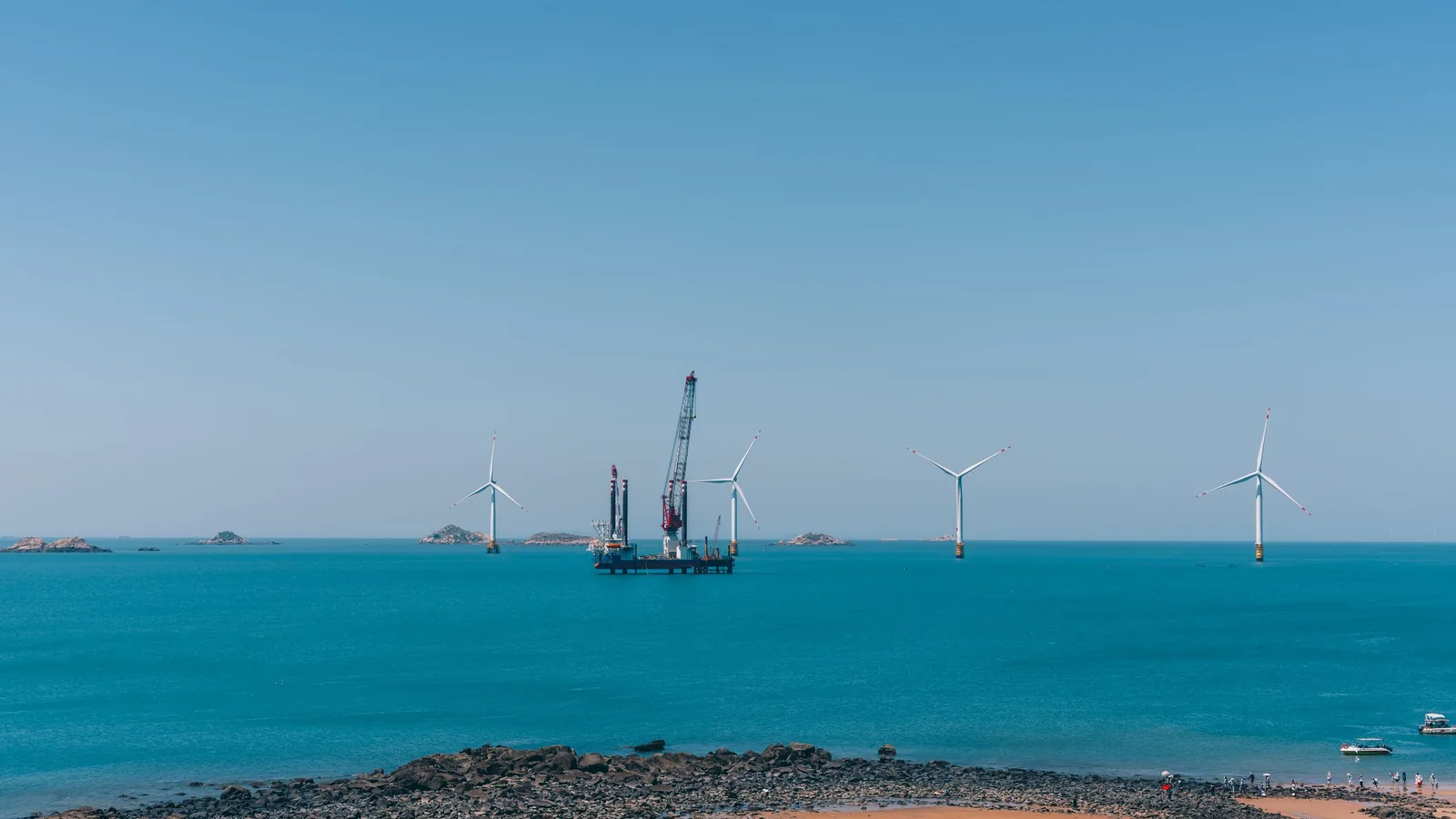 Offshore-Windräder stehen in ruhiger See unter blauem Himmel