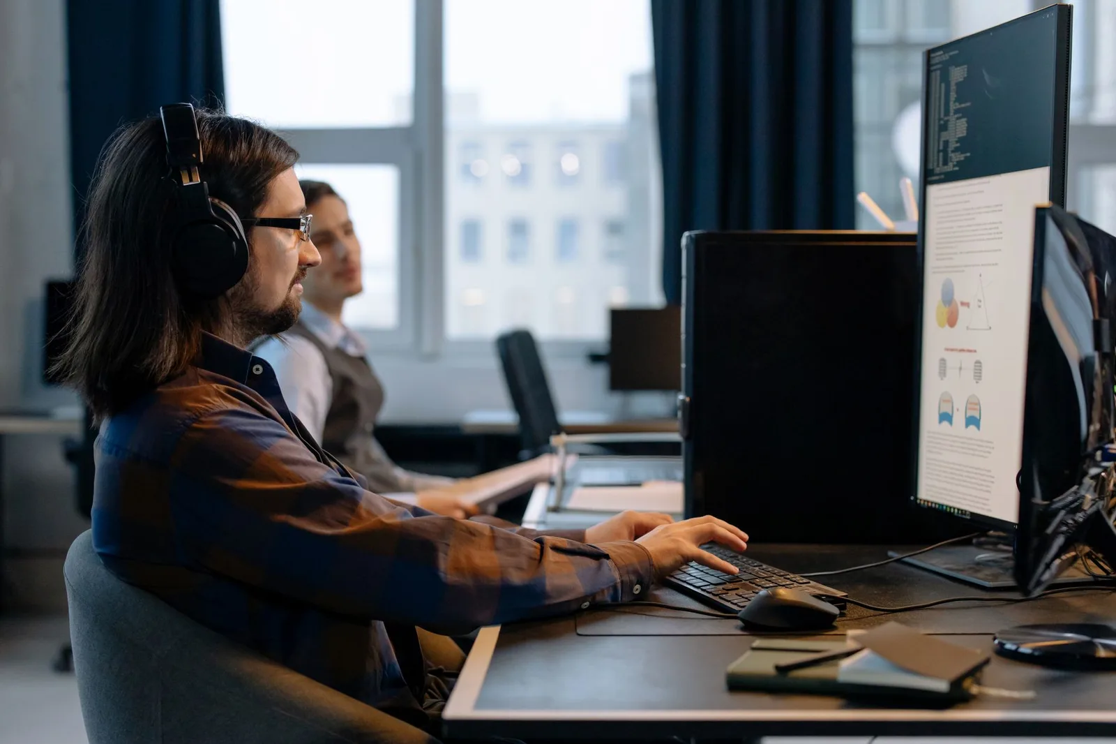 Zwei Entwickler arbeiten gemeinsam an Programmcode an einem Bildschirm in einem modernen Büro
